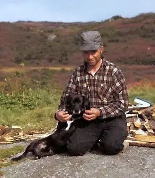 Labrador Retriever history, a fisherman kneeling with a St John's water dog, La Poile, Newfoundland, 1971